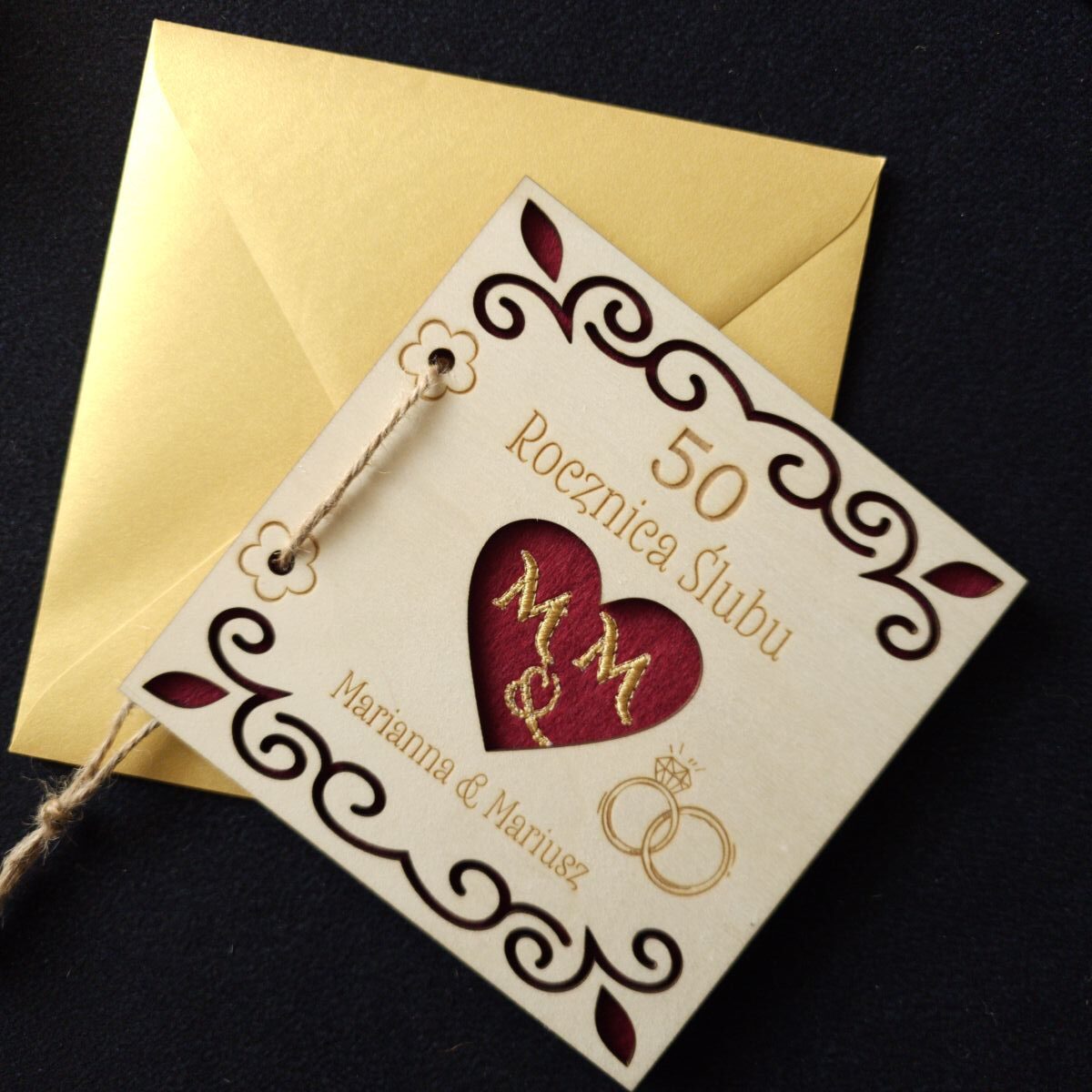 Karta grawerowana personalizowana upominek rocznica ślubu haft koperta dedykacja 15 Personalizowana, drewniana karta upominkowa skrywa w środku haftowany czerwony filc, przewiązana jutowym sznurkiem, zapakowana w złotą, papierową kopertę